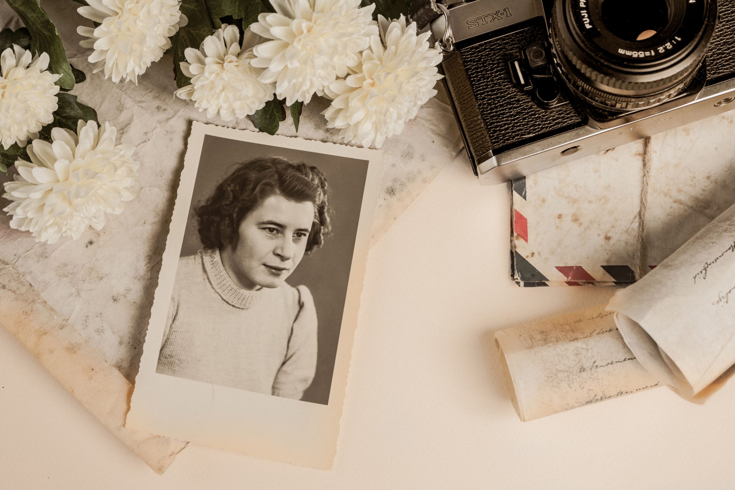 A nostalgic composition featuring a vintage photograph, old camera, and white flowers.
